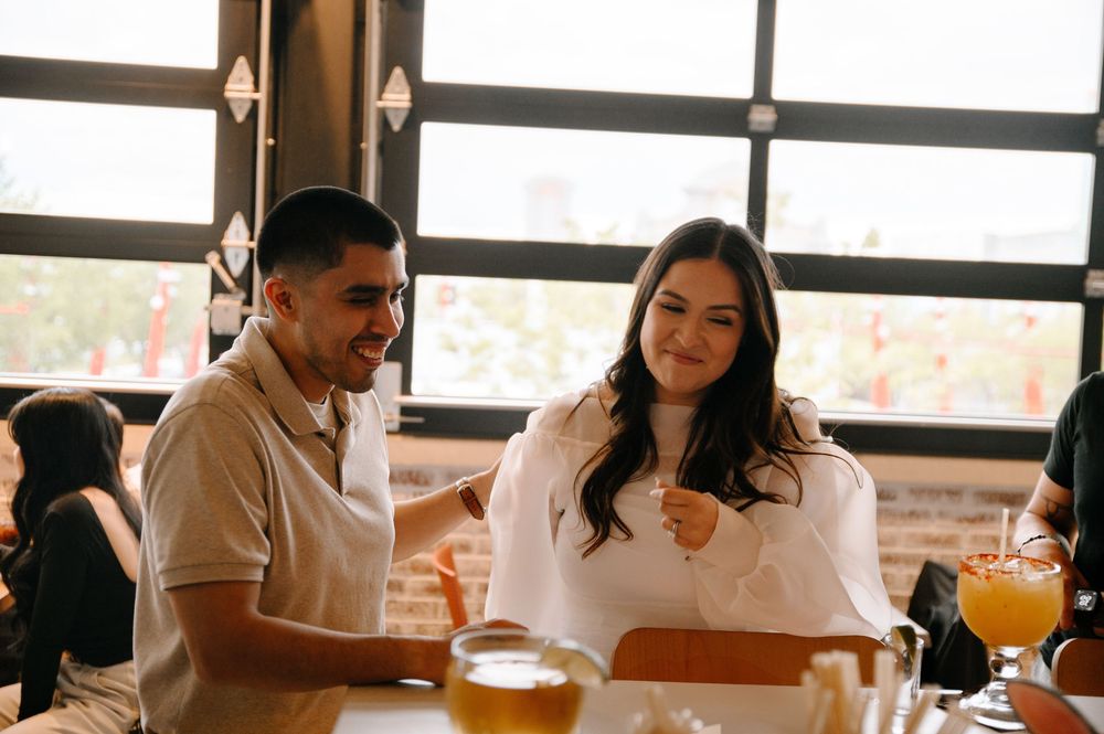 Restaurant gathering with people enjoying drinks near sunlit windows.
