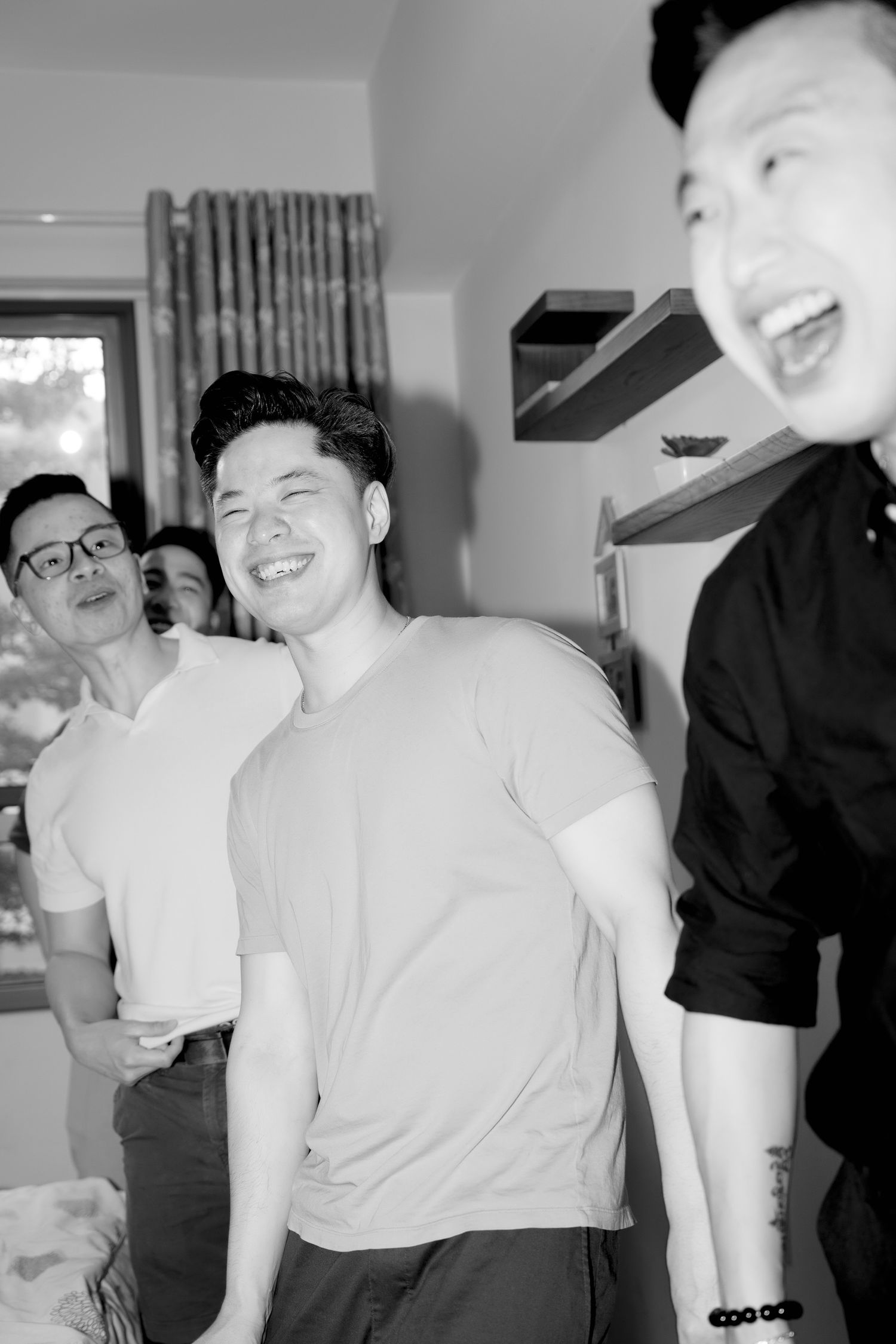 Black and white photo of groomsmen laughing together during wedding preparations.