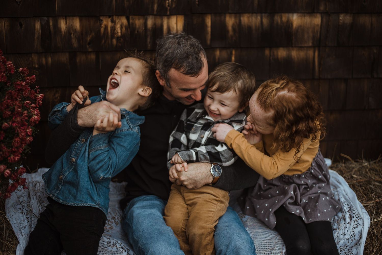 A family shares a joyful moment together while sitting and laughing on a blue couch outdoors.