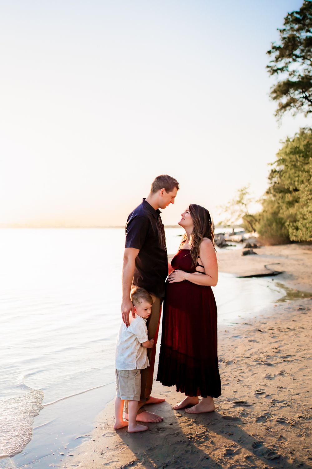 A family shares tender moments together while walking along a sandy beach at sunset.