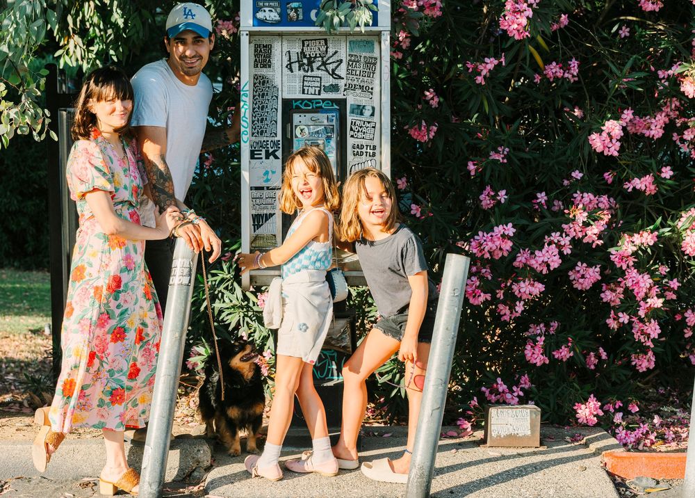 Family walking along path with pink flowering bushes and street signs.