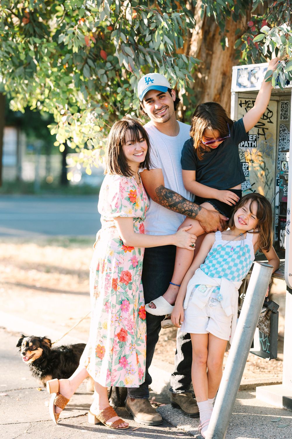 Playful family moment captured under trees near street signs.