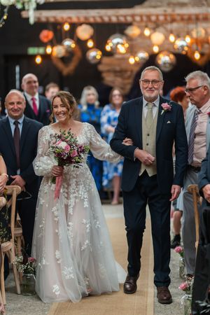 Wedding guests gather in a rustic barn venue decorated with twinkling lights and romantic ambiance.
