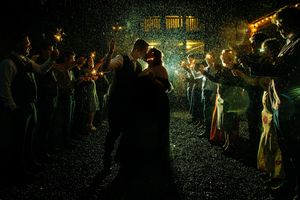 A group of people dancing with sparklers at night creating glowing light trails in the darkness.