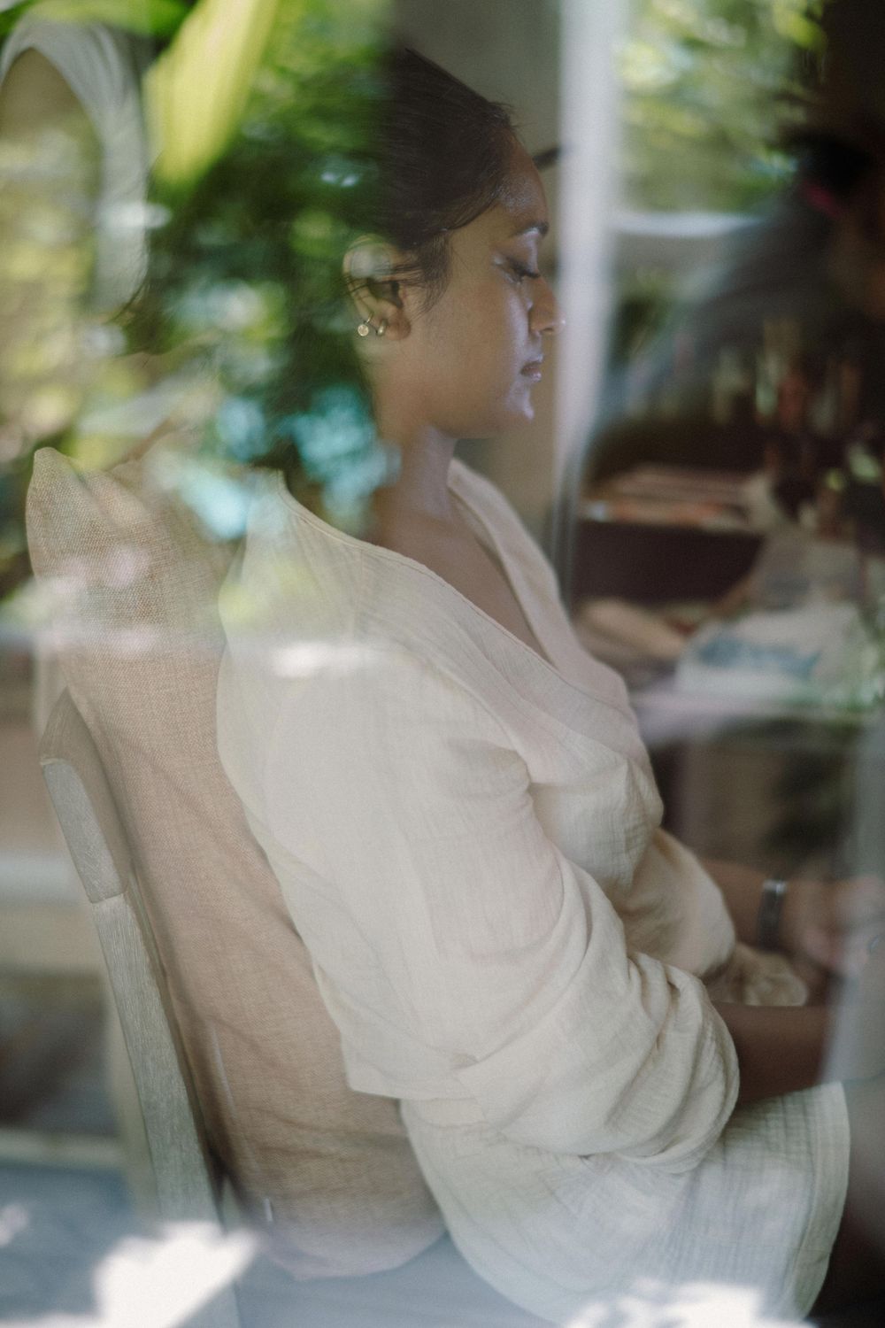 A blurred artistic sequence of motion showing a person in white clothing seated against a soft background with natural light.