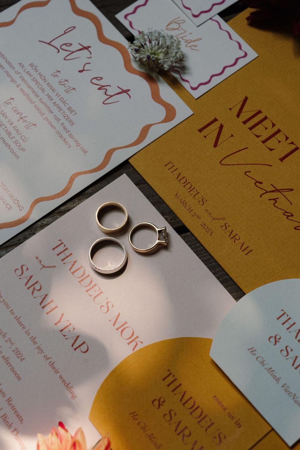 Wedding invitation and rings arranged on beige paper with elegant calligraphy text.