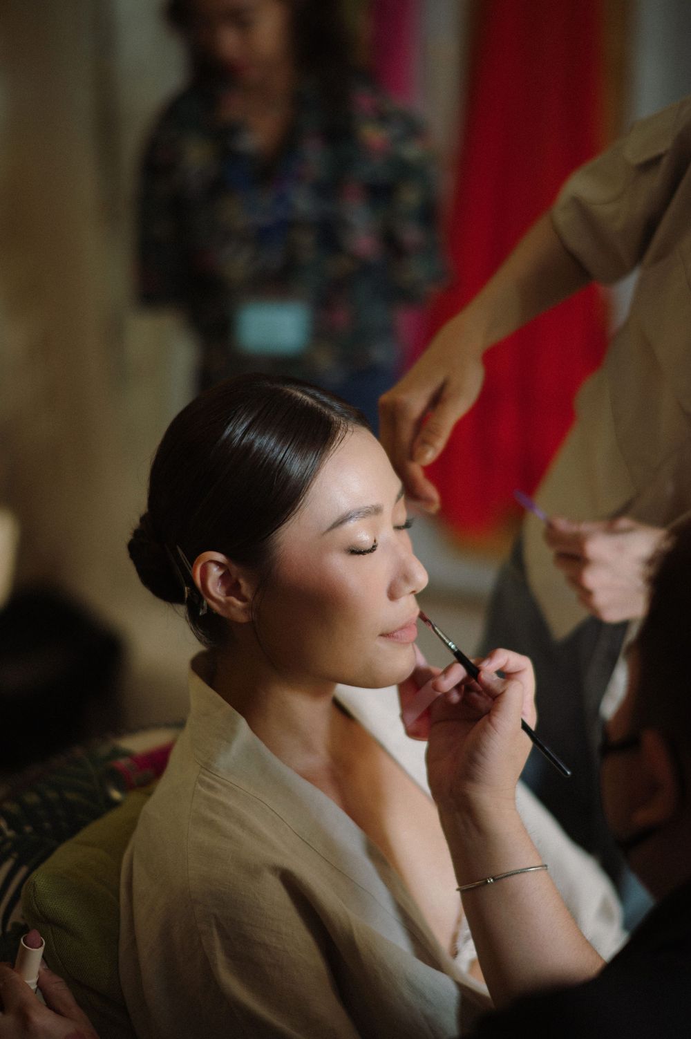 Makeup artist applies finishing touches during wedding day preparations.