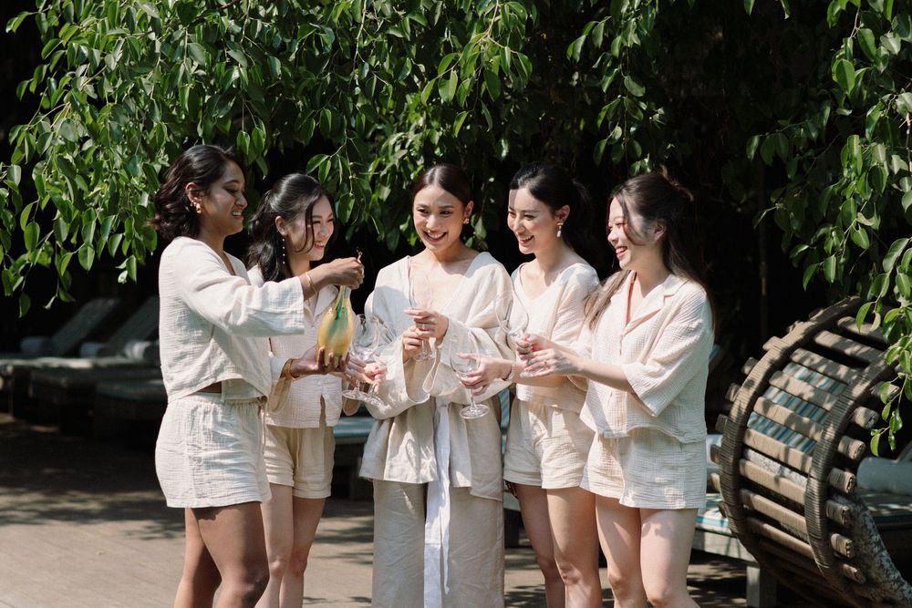 A cheerful group in white outfits gathering outdoors among lush green foliage for a celebration.
