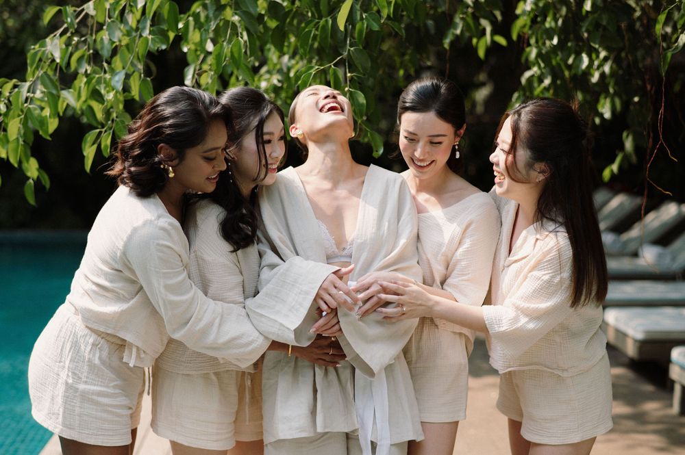 A group in cream-colored outfits sharing a joyful moment together outdoors.