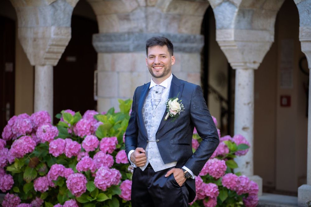 Wedding couple shares joyful moment among pink hydrangeas and stone columns.
