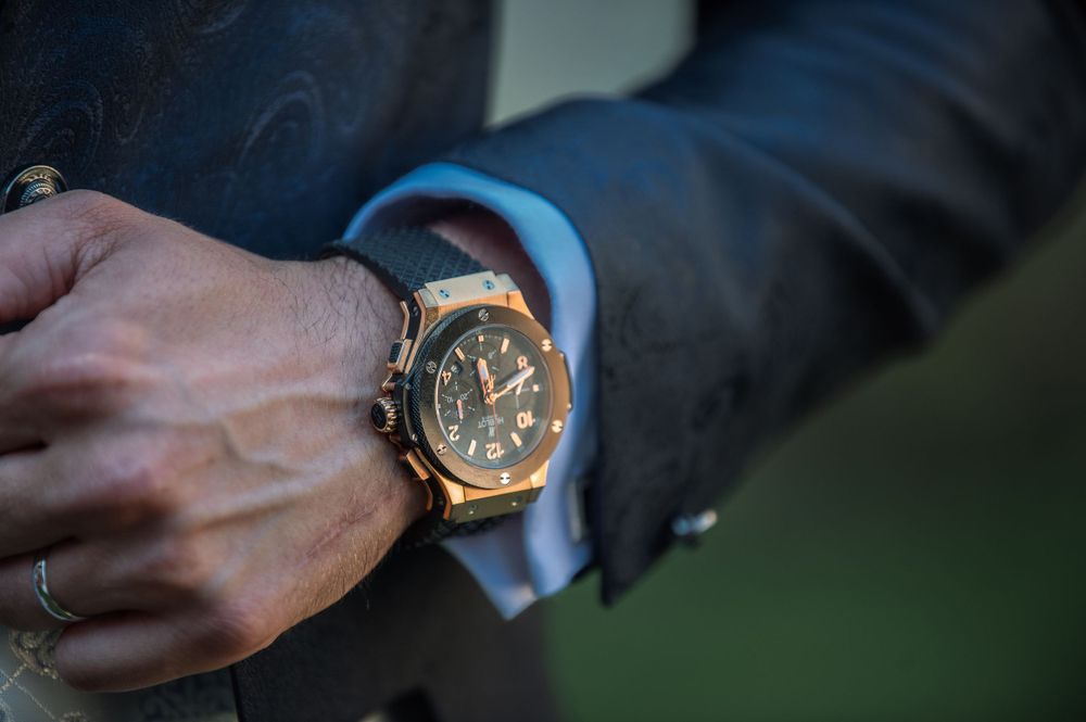 Elegant gold watch detail on groom's wrist with formal attire.