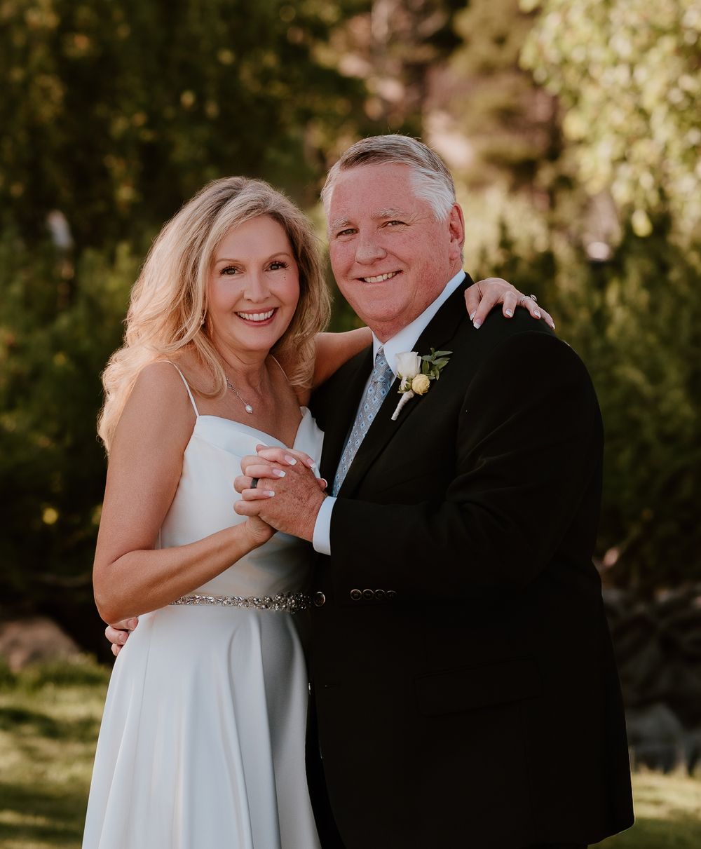 A couple in formal attire shares a romantic moment outdoors during their wedding celebration.