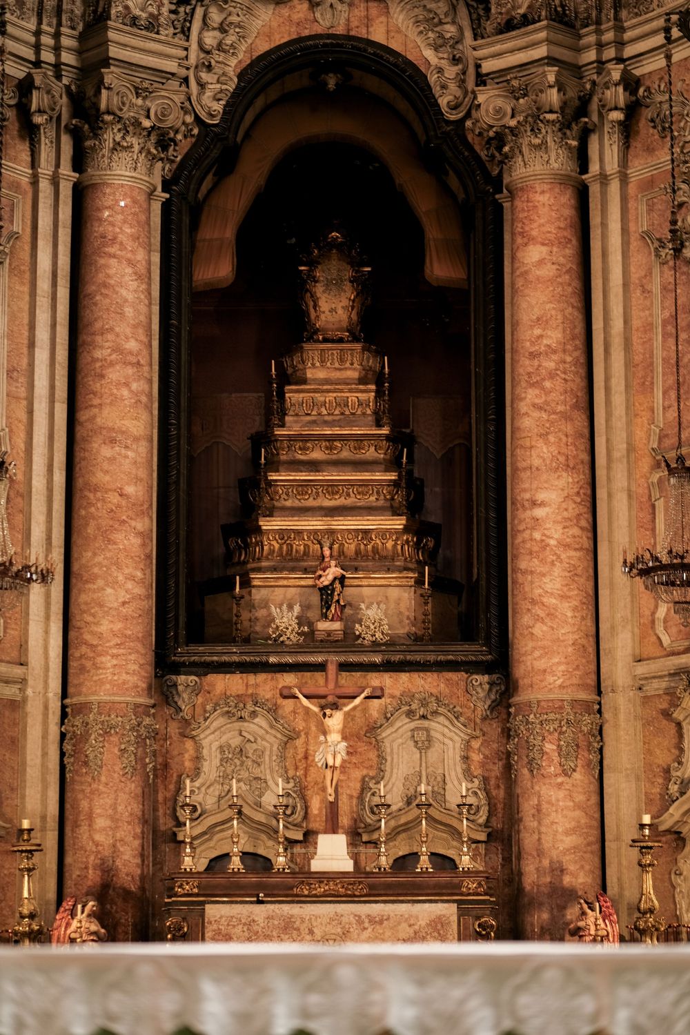Ornate church sanctuary with baroque architecture featuring marble columns, intricate altars and religious statuary.