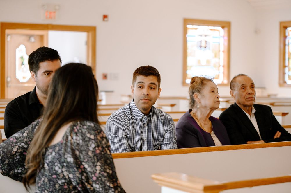 Church congregation seated in rows of wooden pews under natural lighting.