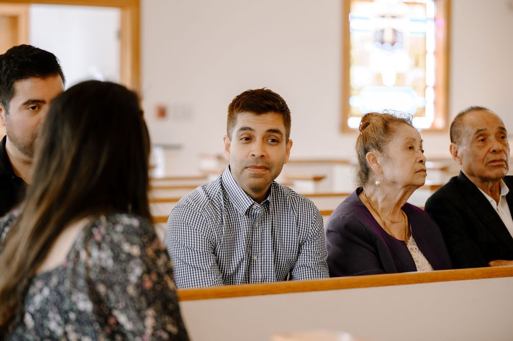 Side view of churchgoers sitting in light-filled sanctuary with wooden pews.