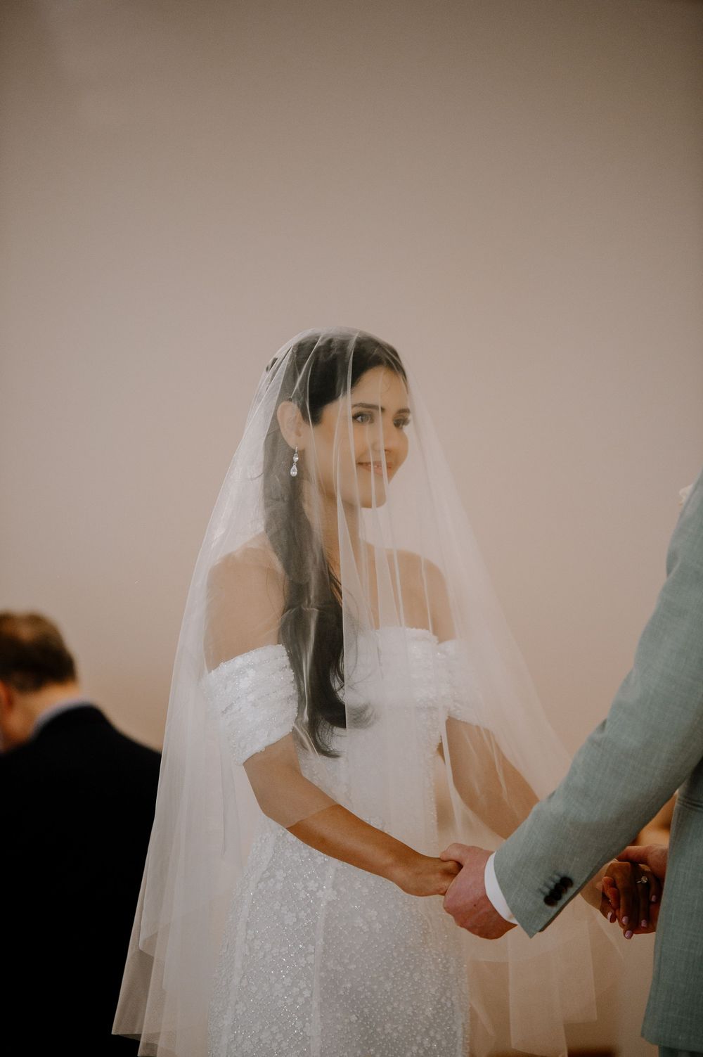 A sequence of wedding photos showing tender moments with the bride in a white dress and veil against a neutral backdrop.