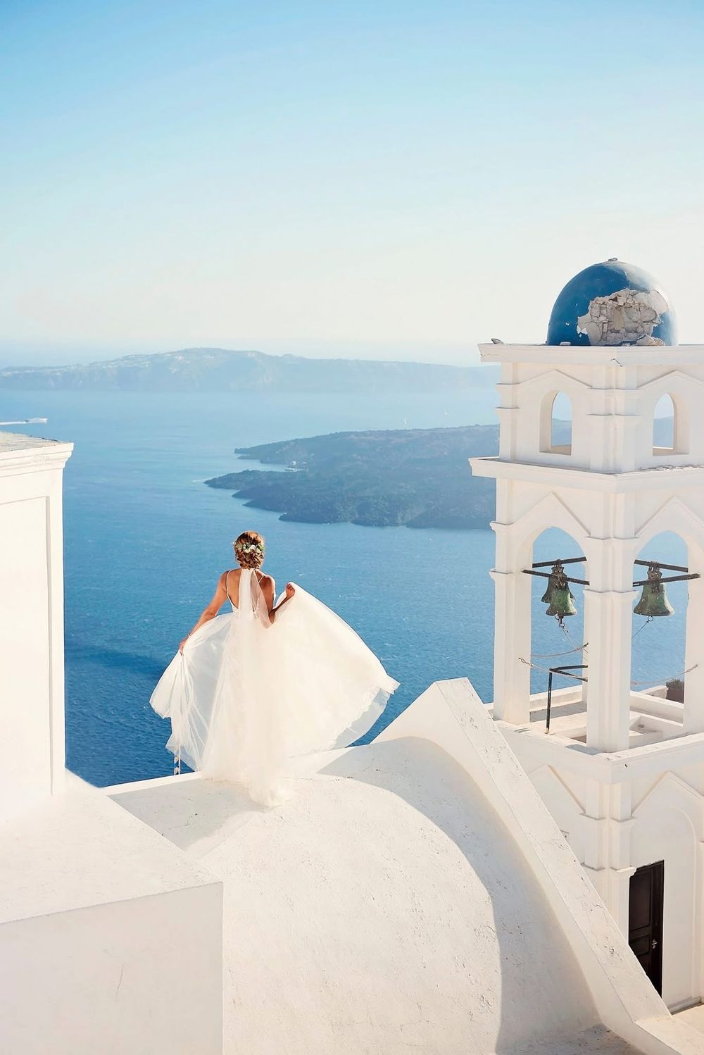 White-washed traditional Greek architecture with blue domed churches overlooking the Aegean Sea in Santorini.