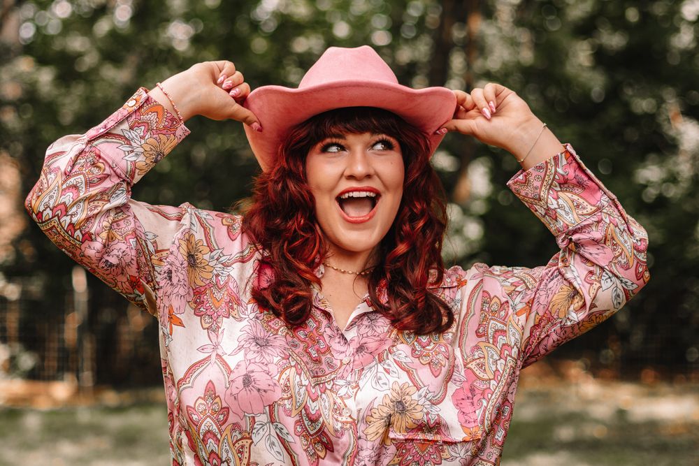 Joyful outdoor portraits showing woman in floral pink blouse and denim.