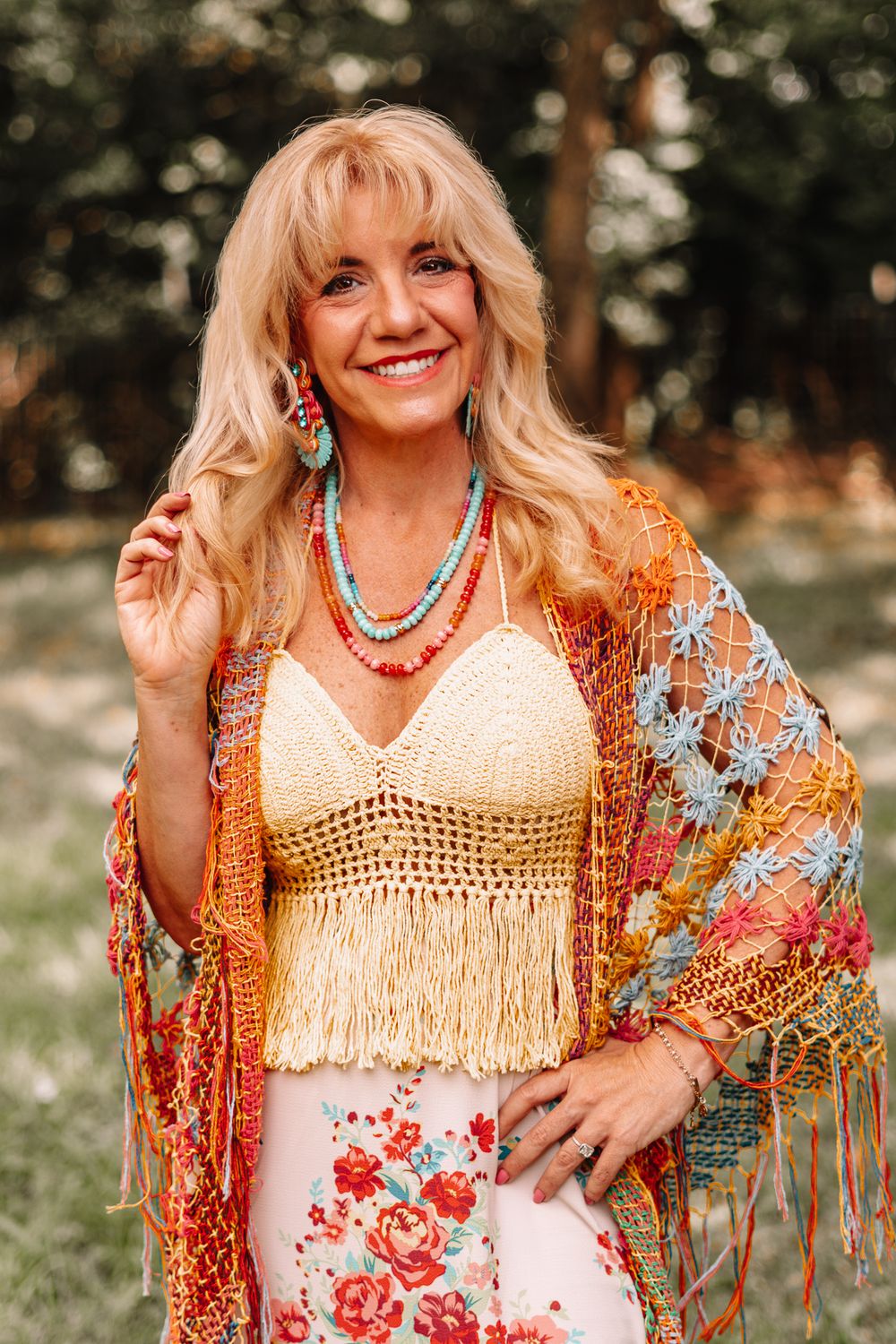 Boho style portrait with fringe vest, turquoise jewelry and floral dress in outdoor setting.