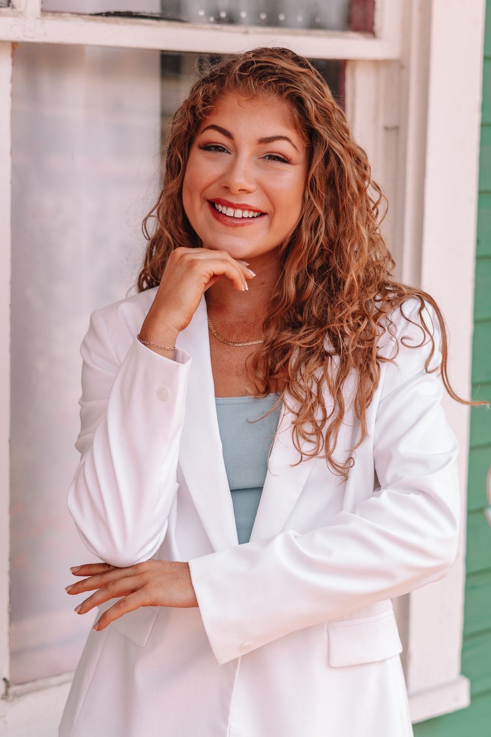 Casual portrait series showing woman in white blazer leaning on pink railing.