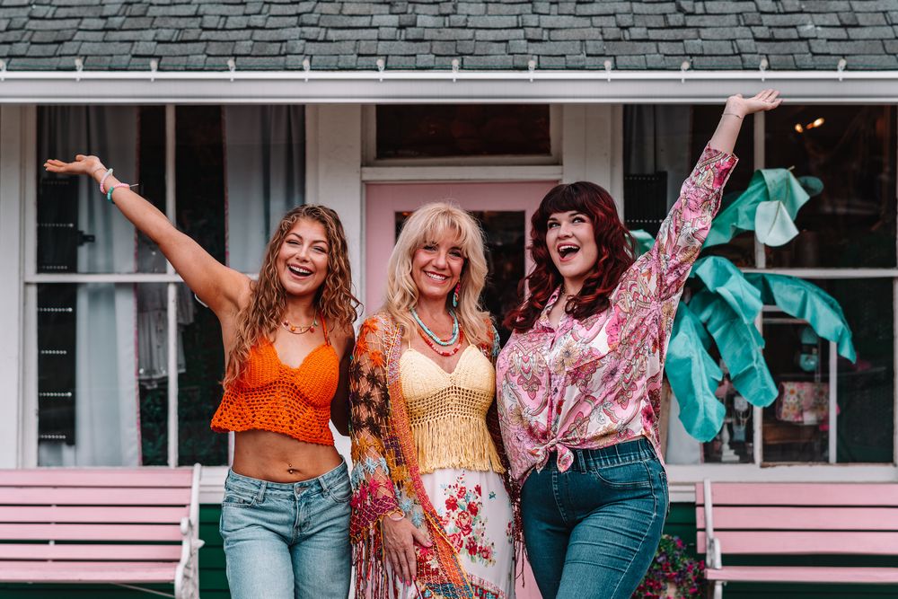 Group photo showing women in colorful boho outfits on pink porch steps.