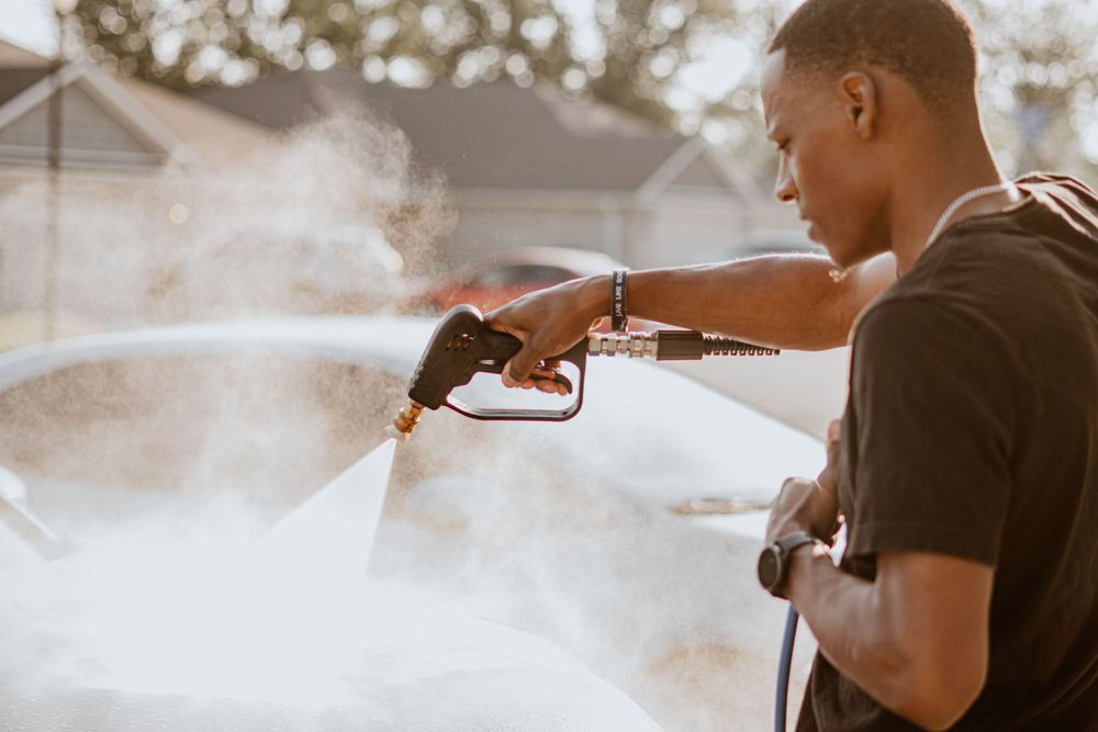 Close-up of pressure washer spray being used to clean car exterior.