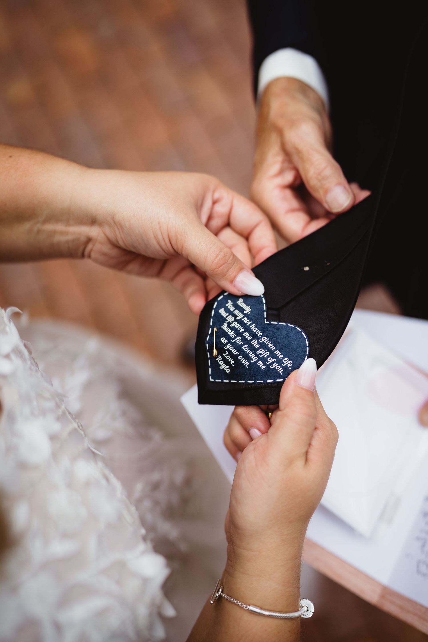 Close-up shot of hands sewing a small navy blue fabric patch with white text onto a garment.
