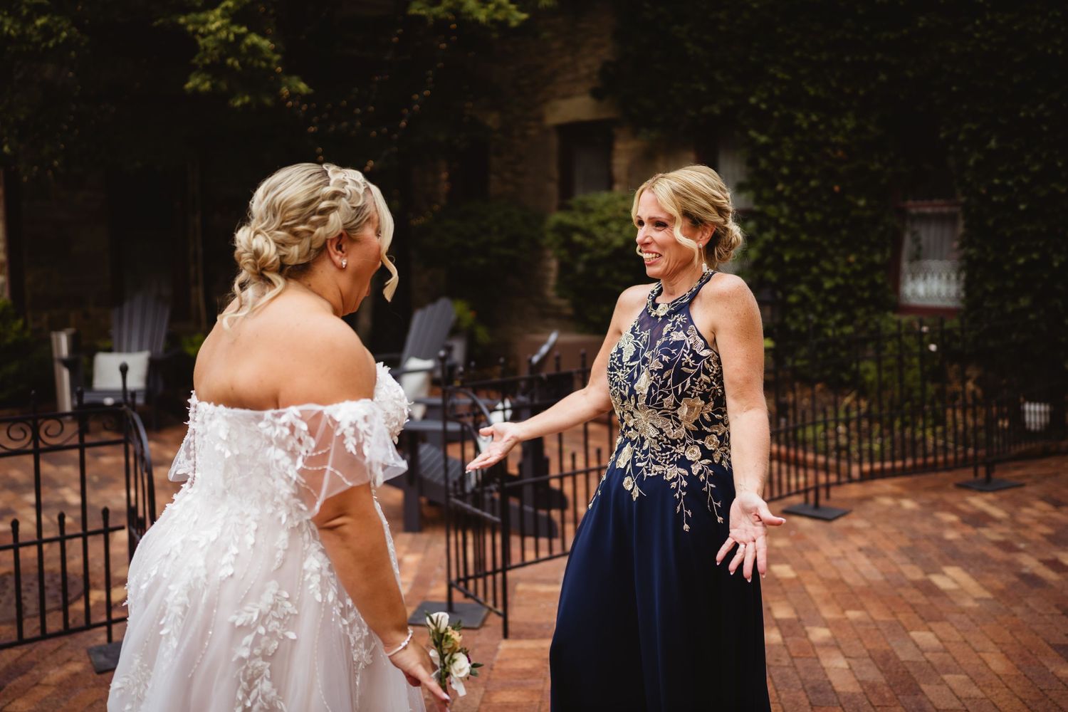 Wedding party in navy blue dresses and formal attire dance together on an outdoor brick patio.