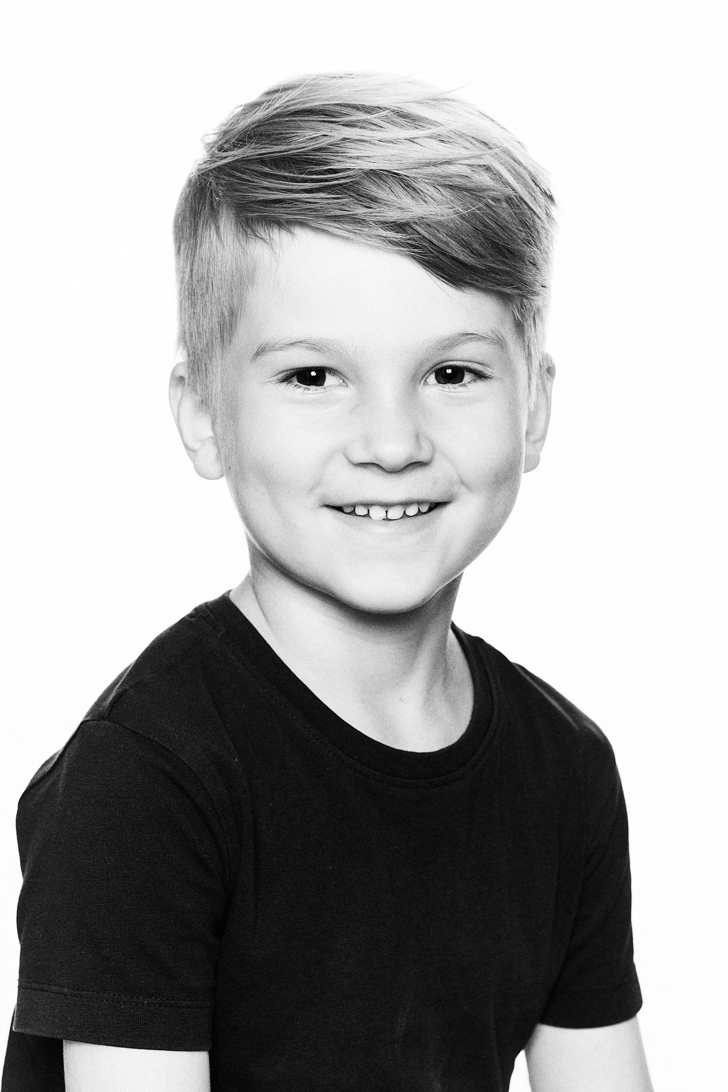 Black and white studio portrait showing a cheerful expression against a plain background.