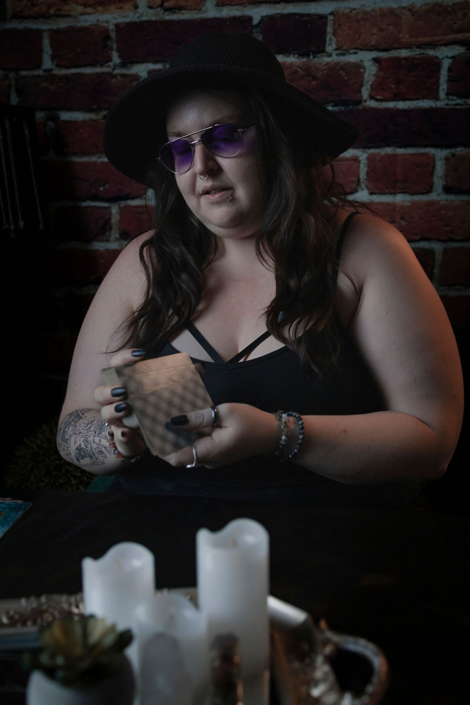 Atmospheric series of moody candlelit photos showing hands and black clothing against exposed brick background.
