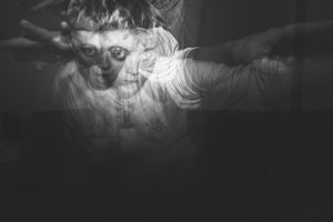 Low-key black and white photographs showing theatrical poses and reactions.