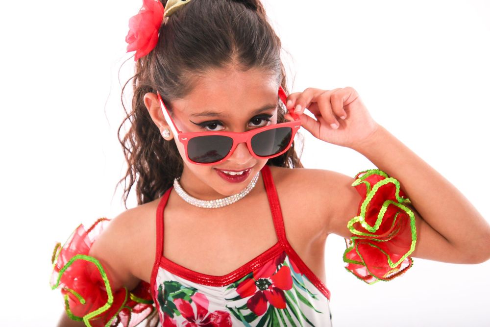 Dance student in floral costume strikes playful poses against white background.