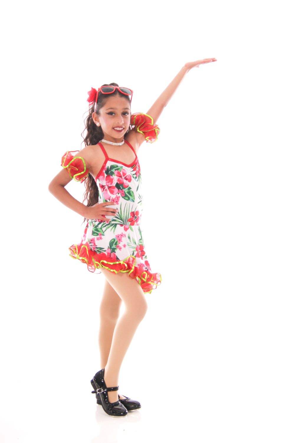 Young dancer in floral dress performs energetic dance moves.