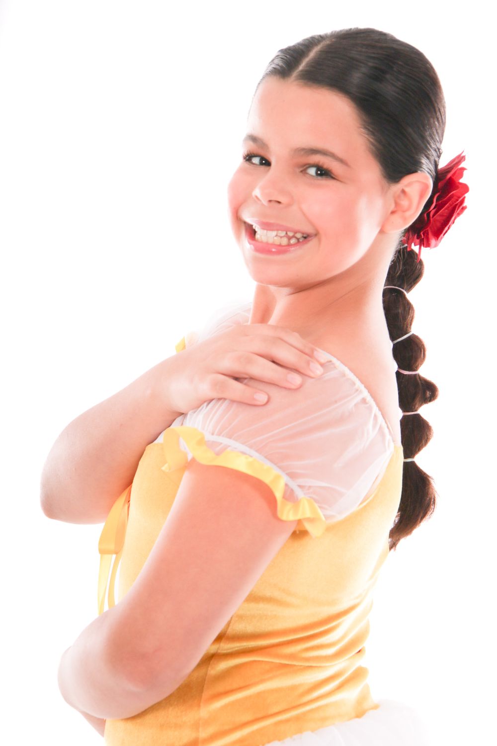Young performer in yellow top poses expressively against white backdrop.