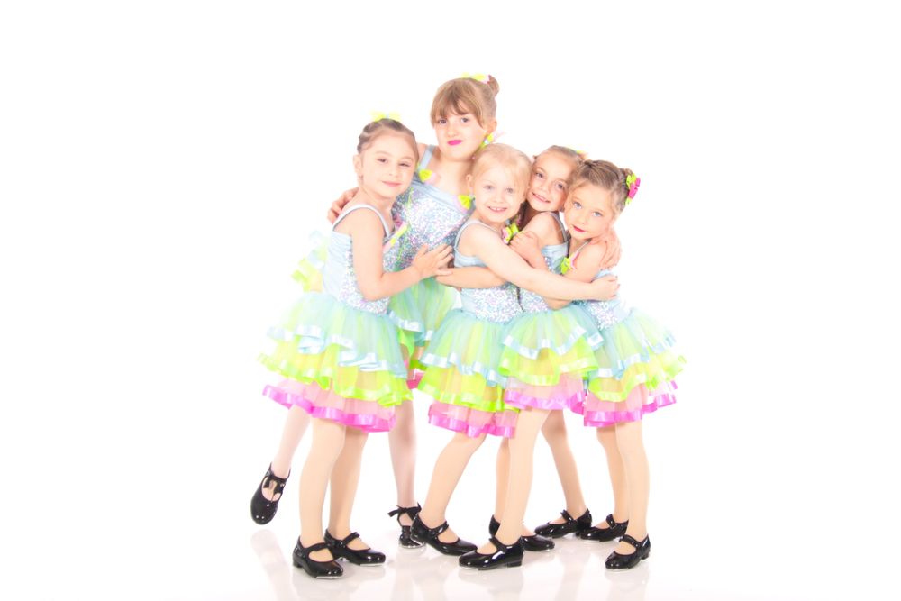 Group of dancers in colorful tutus performing synchronized dance routine.