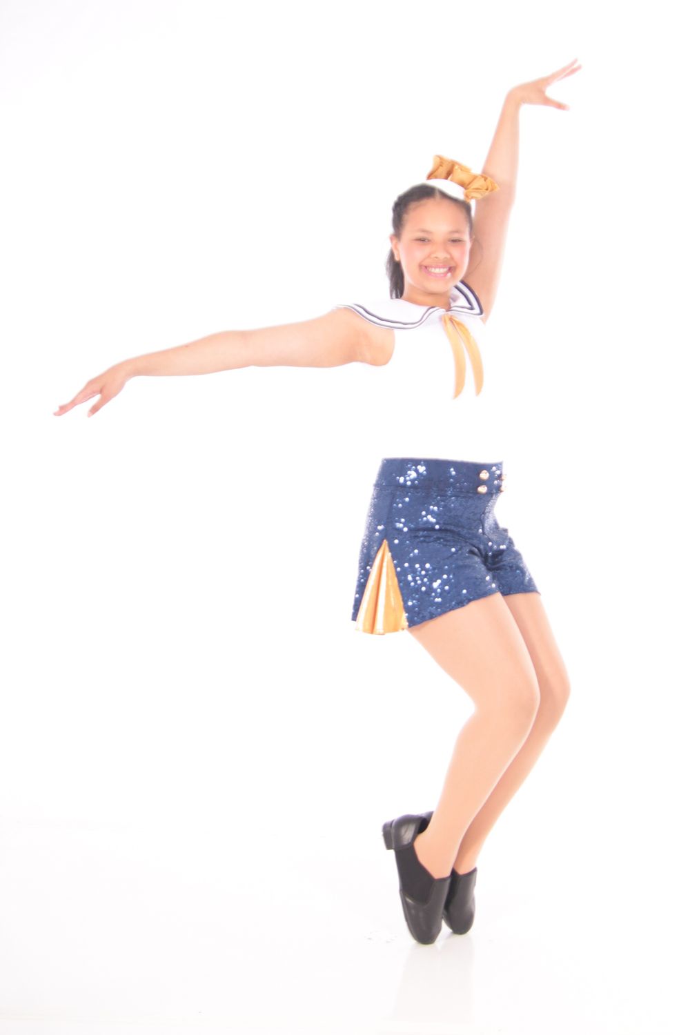 Dancer in blue sequined outfit performing dynamic leaping movements.
