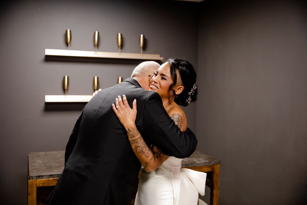An intimate embrace between two people in a dimly lit room with wooden furniture.