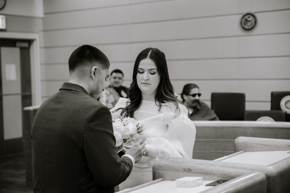 Black and white photograph showing a couple exchanging documents during a courthouse ceremony.