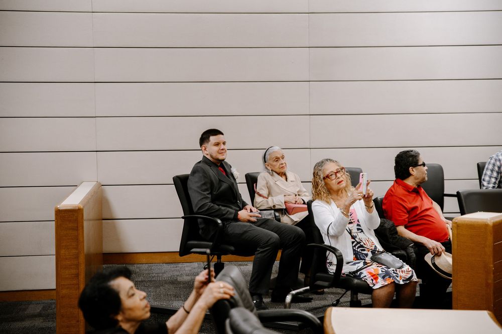 People sitting in a row of chairs in what appears to be a waiting room or office setting.
