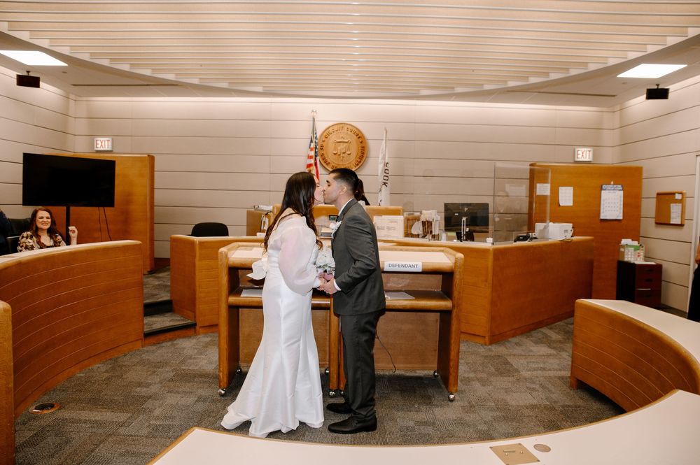 A civil courtroom with wooden benches and walls showing multiple people gathered during a legal proceeding.