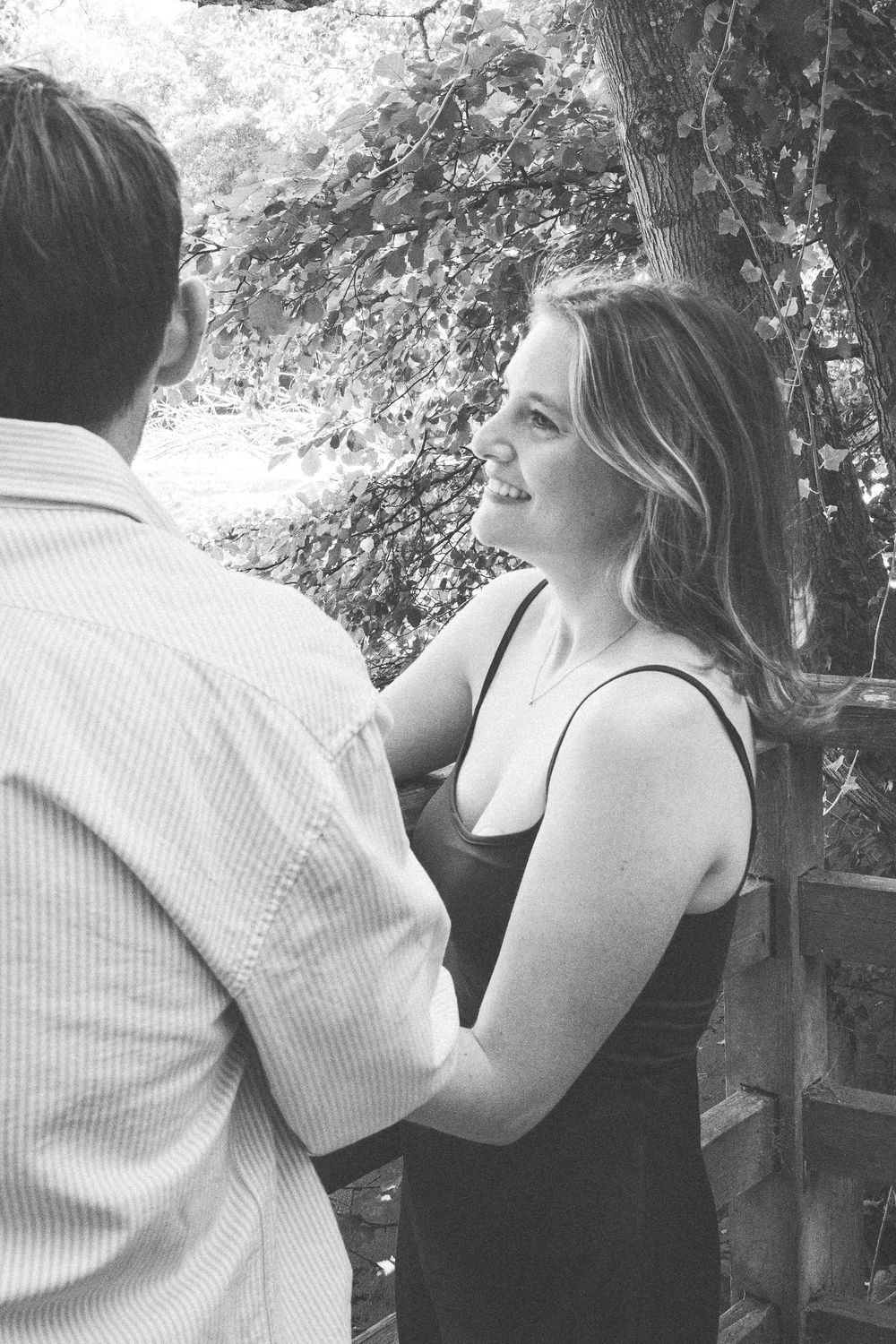 Two people sit closely together outdoors in a candid black and white photo series.