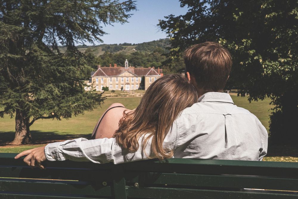 A series of romantic photos showing a couple sitting together on a bench in a scenic park setting at sunset.