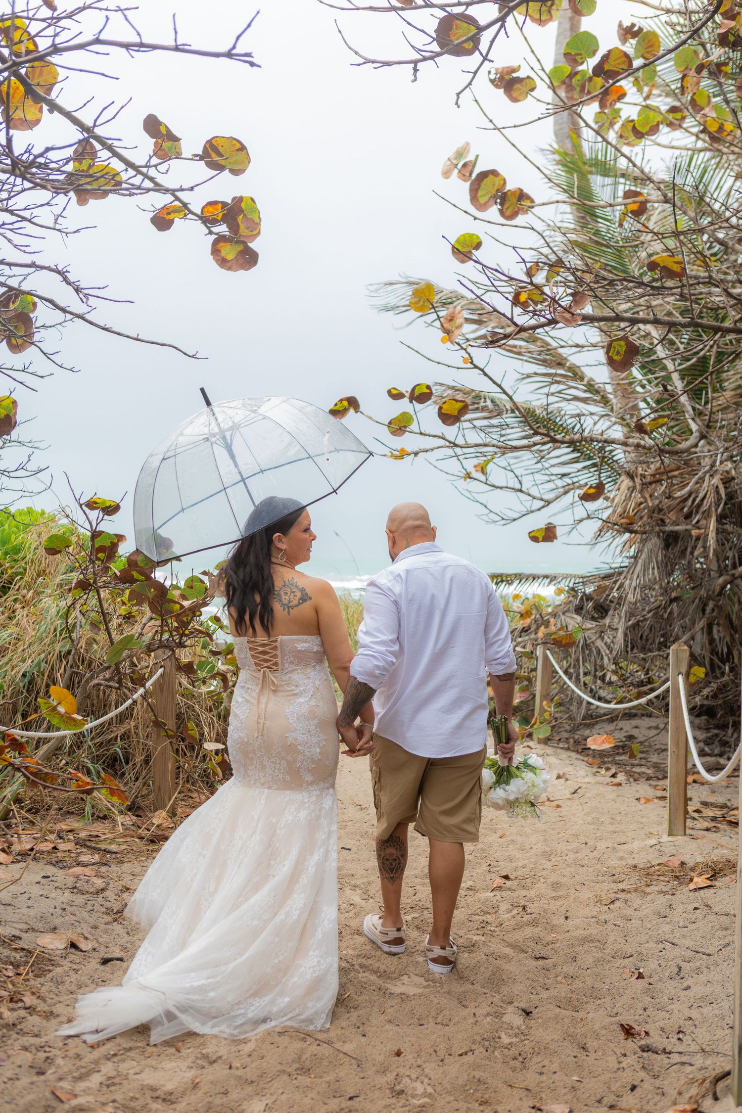 Bride and groom with clear umbrella on hollywood beach