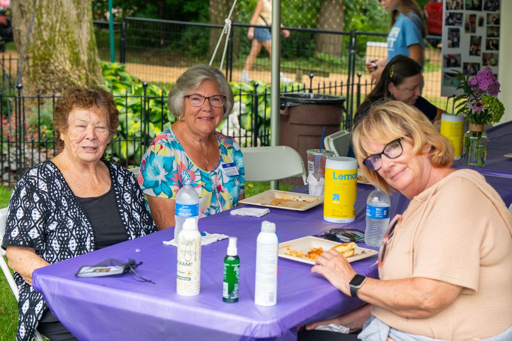 People gathered around purple covered tables at an outdoor community event. Celebration of Life Quad Cities Photography