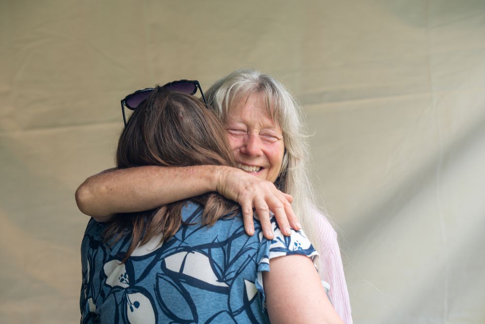 People sharing warm embraces at a community gathering outdoors. Celebration of Life Quad Cities Photography