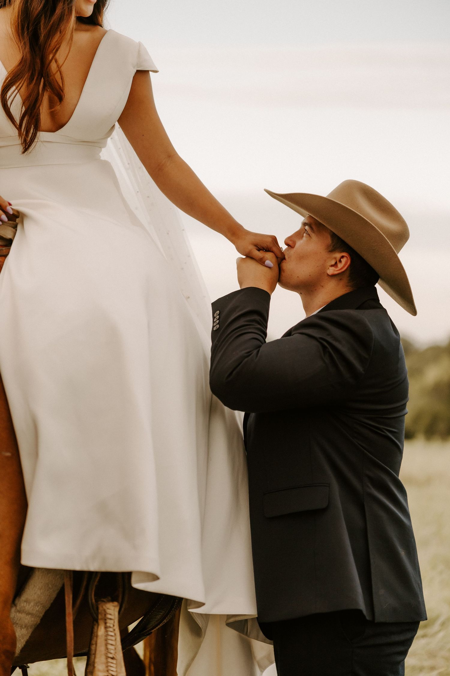 Western-themed wedding with a couple in formal attire, featuring a white dress and cowboy hat in golden light on a horse in Gallatin, TN.
