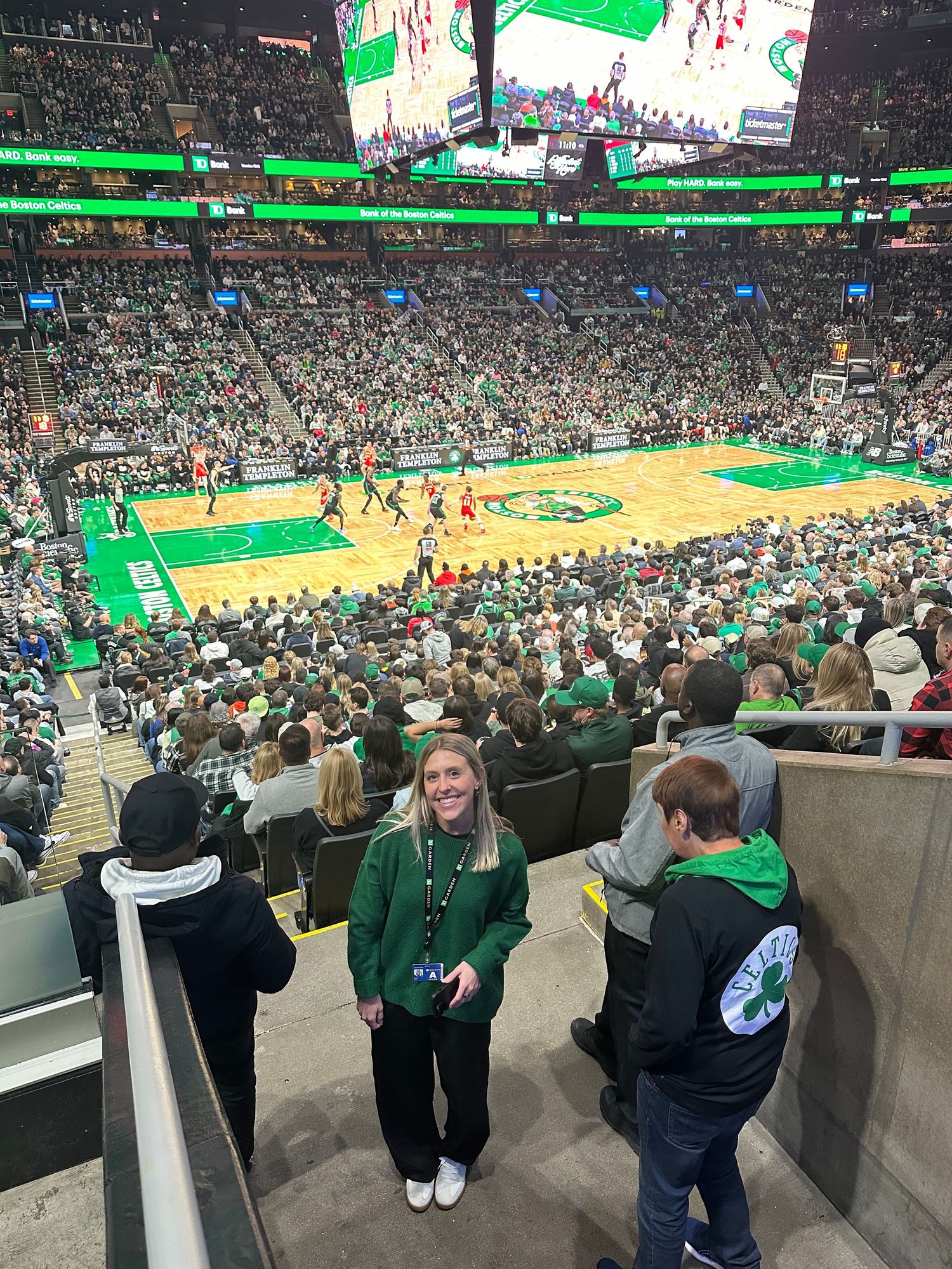 Basketball game at TD Garden arena with packed crowd watching Boston Celtics play on the iconic parquet floor.