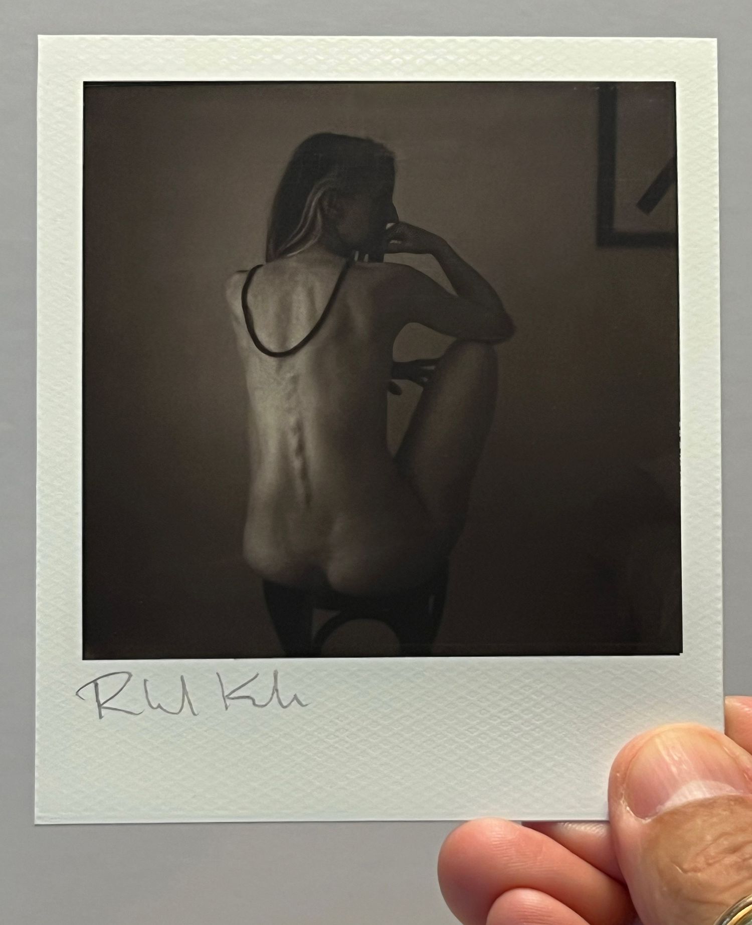 Monochromatic polaroid showing silhouette against dim interior lighting.