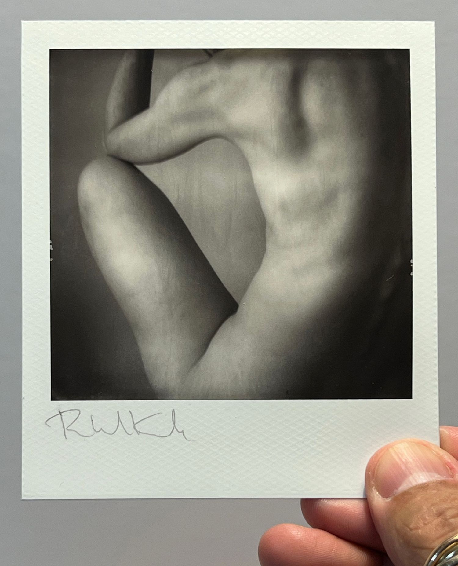 Black and white polaroid of abstract body forms creating curved shadows and highlights.