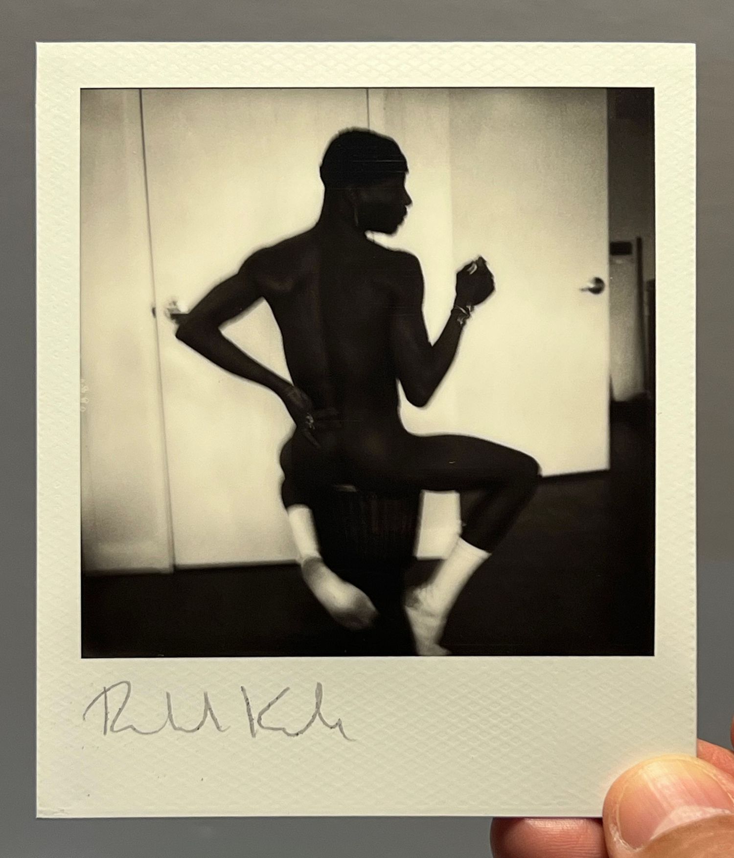 Artistic silhouette polaroid of a figure in motion against light background.